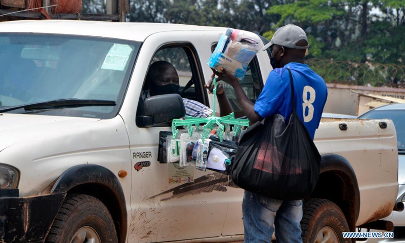 A vendor sells face masks to a man in a vehicle in Kampala, Uganda, on July 4, 2021. Uganda has introduced new penalties for offenders of the country's COVID-19 prevention procedures. A statutory instrument dubbed Public Health (Control of COVID-19) rules 2021, signed by Health Minister Ruth Aceng, said that if one is found guilty of not wearing a facial mask while in public places, he or she will face a jail term of two months.(Photo: Xinhua)