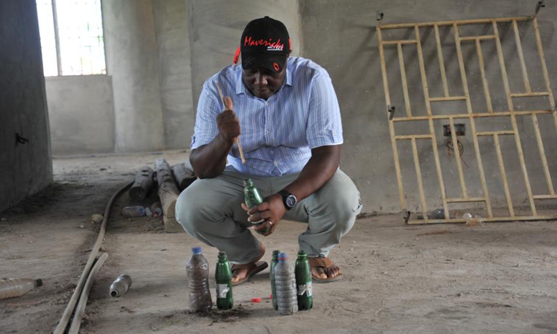 Martial Zohoungbogbo fills soil into recycled plastic bottles inside of the community library he built in Accra, Ghana, on June 24, 2021.(Photo: Xinhua)