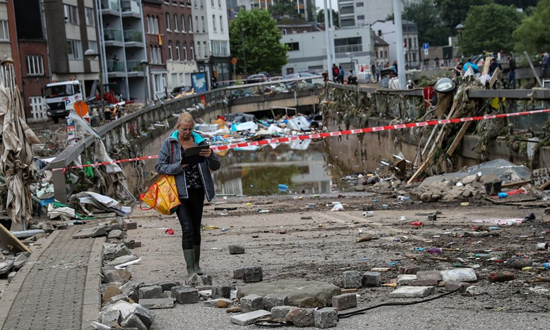 A woman walks past a tunnel filled with garbage after floods in Verviers, Belgium, July 16, 2021.(Photo: Xinhua)