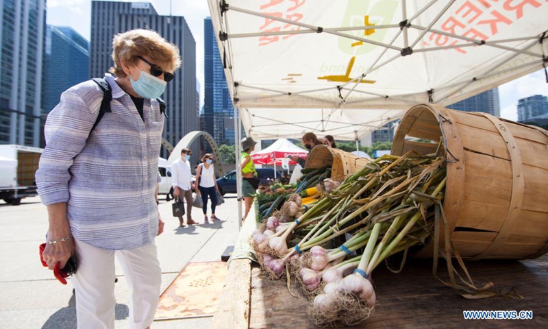 A woman wearing a face mask shops at Nathan Phillips Square Farmers' Market in Toronto, Canada, on July 21, 2021. With fresh fruit, vegetables, honey, maple syrup and flowers, the market opens every Wednesday from May 26 to Oct. 13 this year. (Photo: Xinhua)