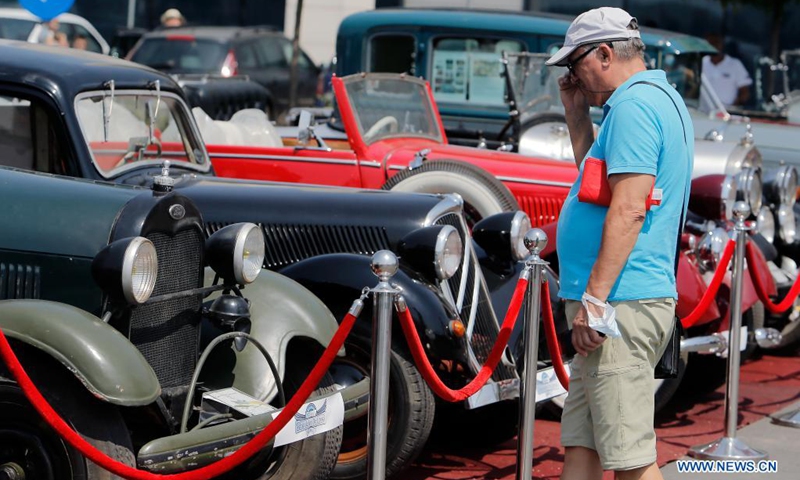 A man looks at a collection of cars on display during the Old Cars Show 2021 organized by Romania's Vintage Vehicle Club in Bucharest, Romania, July 31, 2021.(Photo: Xinhua)