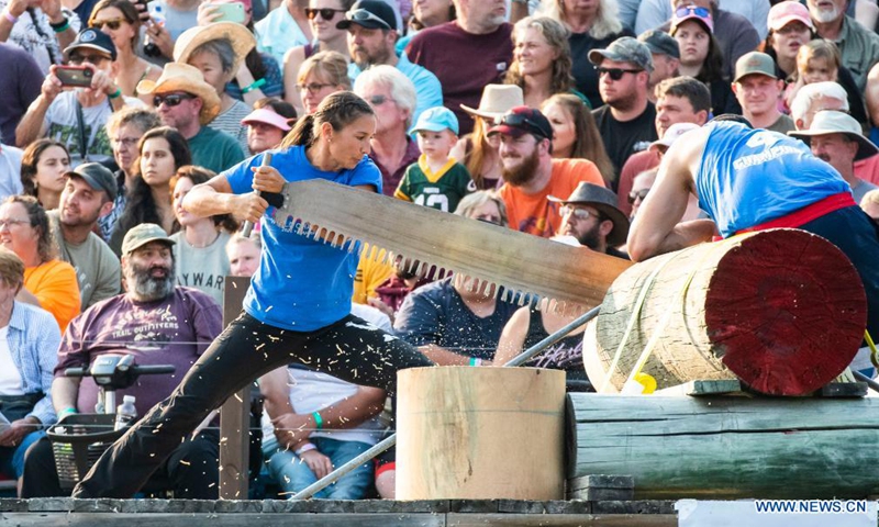 A woman uses a crosscut saw to cut wood during the 61st Lumberjack World Championships in Hayward, Wisconsin, the United States, on July 31, 2021. The championships held here showcased lumberjacks and lumberjills competing in sawing, chopping, speed climbing, log rolling, and boom-running.(Photo: Xinhua)