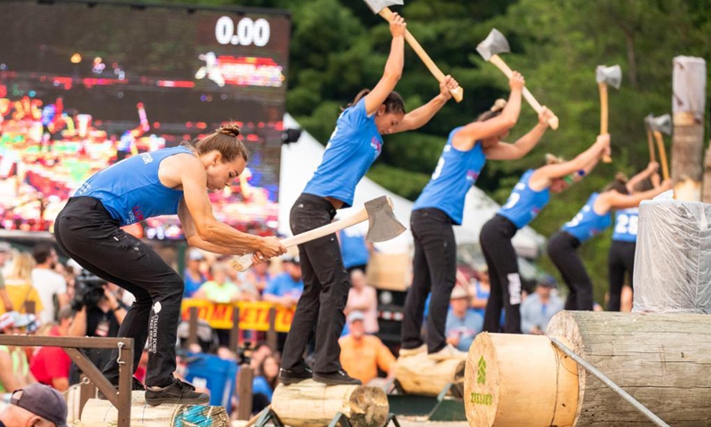 Competitors use axes to chop wood during the 61st Lumberjack World Championships in Hayward, Wisconsin, the United States, on July 31, 2021. The championships held here showcased lumberjacks and lumberjills competing in sawing, chopping, speed climbing, log rolling, and boom-running.(Photo: Xinhua)