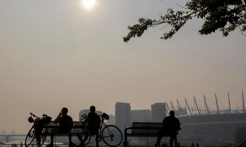 People sit at a park under the smoky sky in Vancouver, British Columbia, Canada, Aug. 13, 2021. Vancouver was shrouded in smoke haze on Friday due to wildfires.Photo:Xinhua