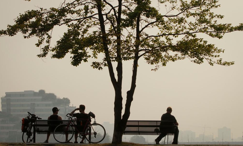 People sit at a park under the smoky sky in Vancouver, British Columbia, Canada, Aug. 13, 2021. Vancouver was shrouded in smoke haze on Friday due to wildfires.Photo:Xinhua