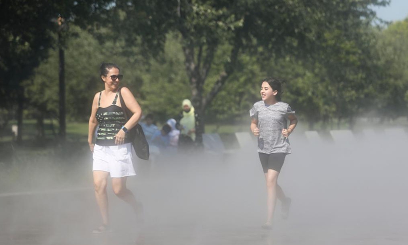 People walk in the mist garden near the Unisphere in Flushing Meadows Corona Park in New York, the United States, Aug. 13, 2021. A heat wave recently hit New York City.Photo:Xinhua