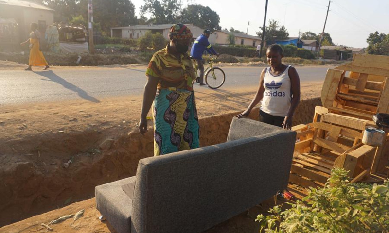 Beatrice Nanyangwe (R, Front), a female carpenter, shows a couch to a customer in Ndola, capital of Copperbelt province, Zambia, on Aug. 7, 2021.(Photo: Xinhua)