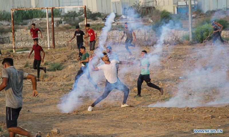 A Palestinian protester throws back a tear gas canister during a protest to mark 52nd anniversary of burning Al-Aqsa Mosque in East Jerusalem, on the Gaza-Israel border in east of southern Gaza Strip city of Khan Younis, Aug. 21, 2021. Dozens of Palestinian protesters were injured on Saturday in clashes with Israeli soldiers near the border between eastern Gaza Strip and Israel, Palestinian medics said. (Photo: Xinhua)