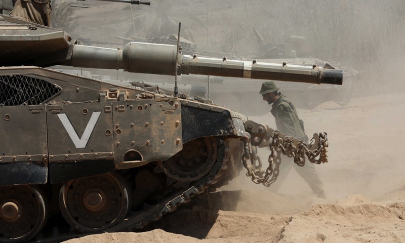 An Israeli soldier walks by the tanks as the troops patrol near the Israel-Gaza border on Aug. 25, 2021.(Photo: Xinhua)