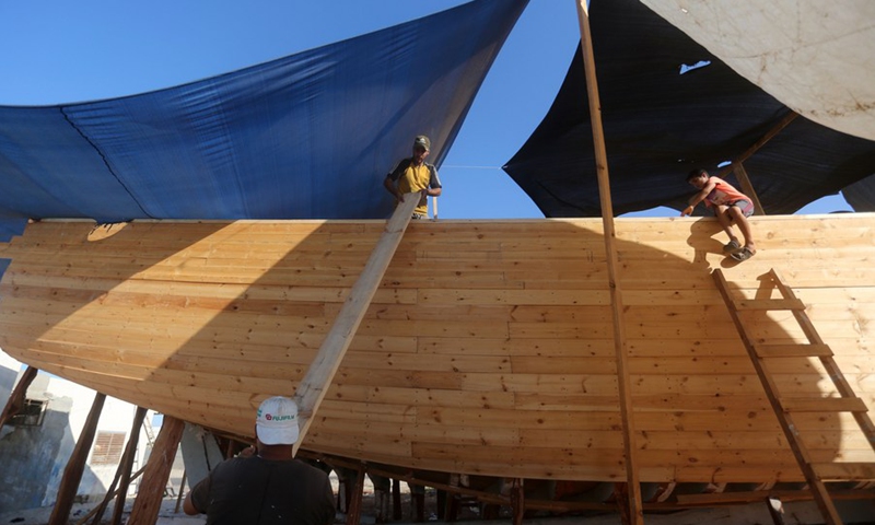 The sons of Palestinian boat maker Abdullah Al-Najjar help in making a new boat at a port in the southern Gaza Strip city of Khan Younis, on Sept. 5, 2021.(Photo: Xinhua)