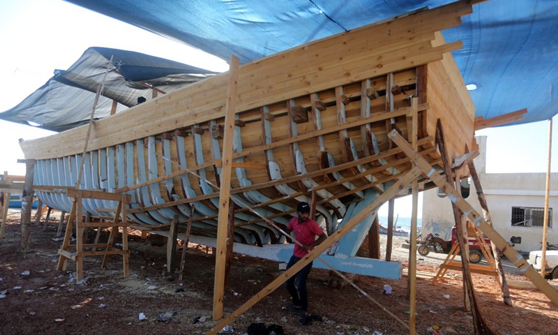 The son of Palestinian boat maker Abdullah Al-Najjar helps in making a new boat at a port in the southern Gaza Strip city of Khan Younis, on Sept. 5, 2021.(Photo: Xinhua)