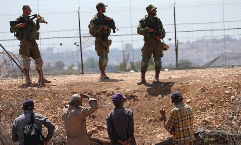 Palestinian workers are stopped by Israeli soldiers guarding a fence amid a manhunt for the six Palestinians who escaped from an Israeli prison, near the village of Muqeibila, northern Israel, on Sept. 9, 2021.(Photo: Xinhua)