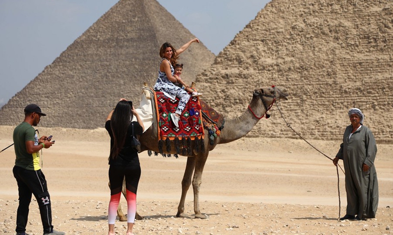 Two tourists riding a camel pose for photos in front of the Pyramids of Giza, Egypt, on Sept. 27, 2021.(Photo: Xinhua)