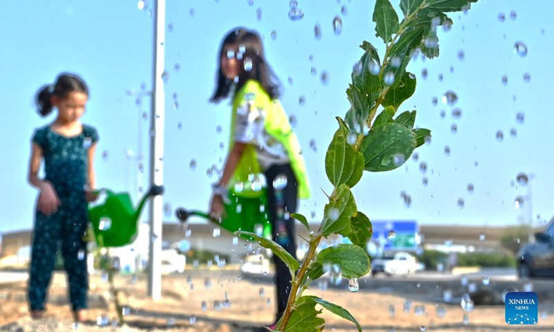 Children water a sapling during a tree-planting campaign in Capital Governorate, Kuwait, on Oct. 2, 2021. Kuwait launched on Saturday a tree-planting campaign in the Capital Governorate in an endeavor to address climate challenges.(Photo: Xinhua)