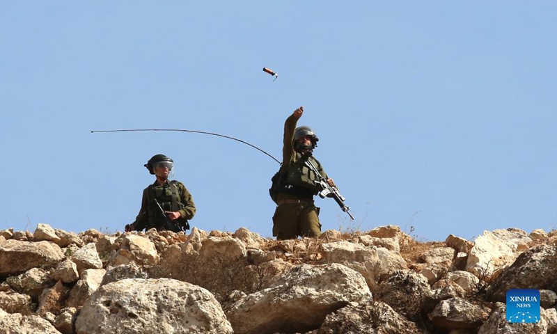 An Israeli soldier throws a tear gas canister at Palestinian protesters during a protest against the expansion of Jewish settlements in the West Bank village of Beit Dajan, east of Nablus, Oct. 15, 2021.Photo:Xinhua