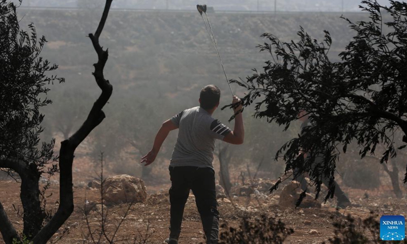 A protester uses a slingshot to hurl a stone at Israeli soldiers following a protest against the expanding of Jewish settlements in the village of Beita, south of the West Bank city of Nablus, Oct. 15, 2021.Photo:Xinhua