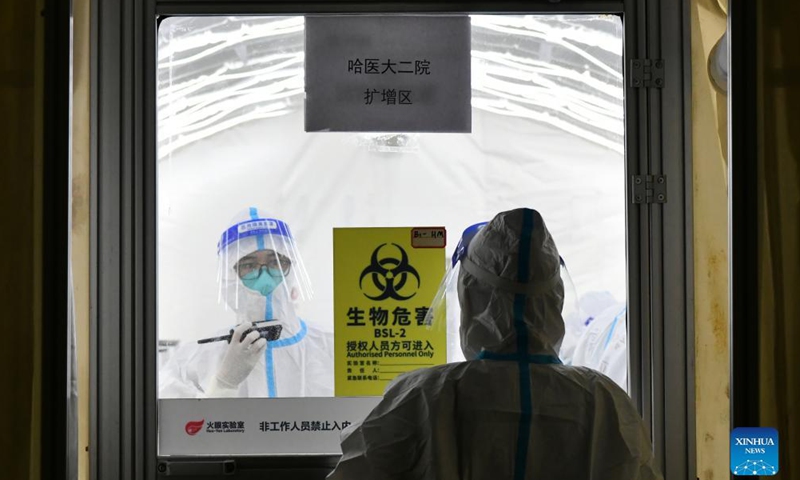 A medical worker talks with a colleague inside an air-inflated film chamber of a mobile laboratory for nucleic acid test in Harbin, northeast China's Heilongjiang Province, Nov. 5, 2021.Photo:Xinhua