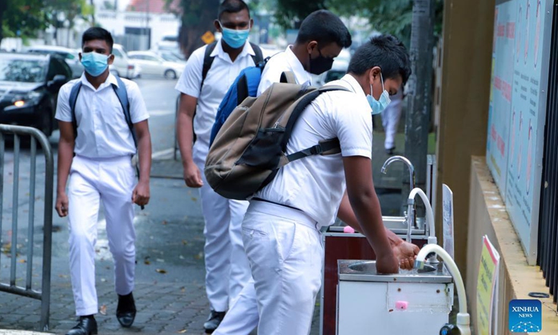 Students wearing face masks wash their hands before entering a school in Colombo, Sri Lanka, on Nov. 8, 2021. Academic activities in grades 10, 11, 12 and 13 in all schools across Sri Lanka resumed from Monday.(Photo: Xinhua)