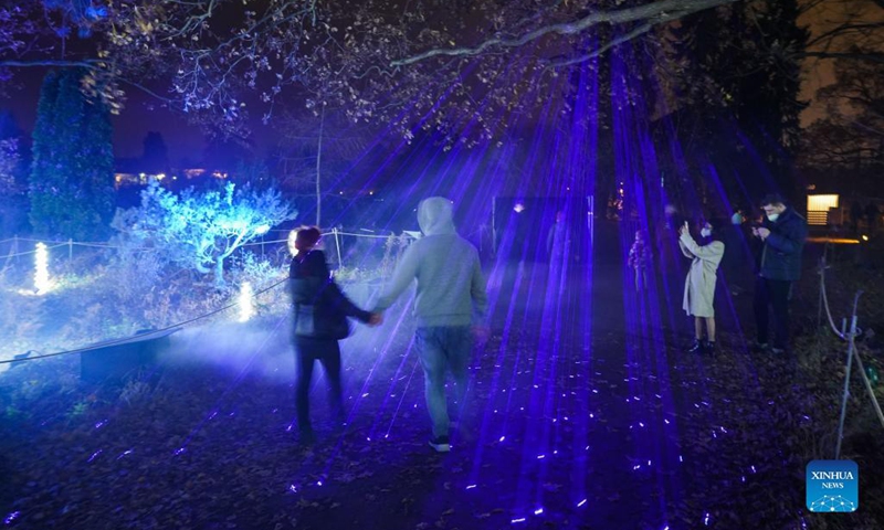 Two visitors walk past light decorations during the Christmas Garden Berlin light show at Berlin-Dahlem Botanical Garden in Berlin, capital of Germany, Nov. 19, 2021. The Christmas Garden Berlin kicked off on Friday and will last until Jan. 9, 2022. (Photo by Stefan Zeitz/Xinhua)