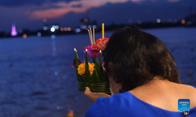 A woman prepares to set afloat a water lantern in Chao Phraya River during the Loy Krathong Festival in Bangkok, Thailand, on Nov. 19, 2021.Photo:Xinhua