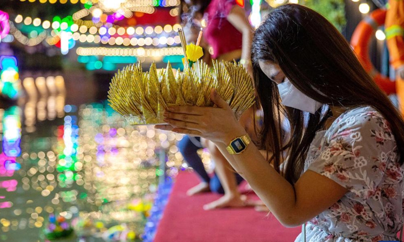 A woman prepares to set afloat a water lantern in Chao Phraya River during the Loy Krathong Festival in Bangkok, Thailand, on Nov. 19, 2021.Photo:Xinhua