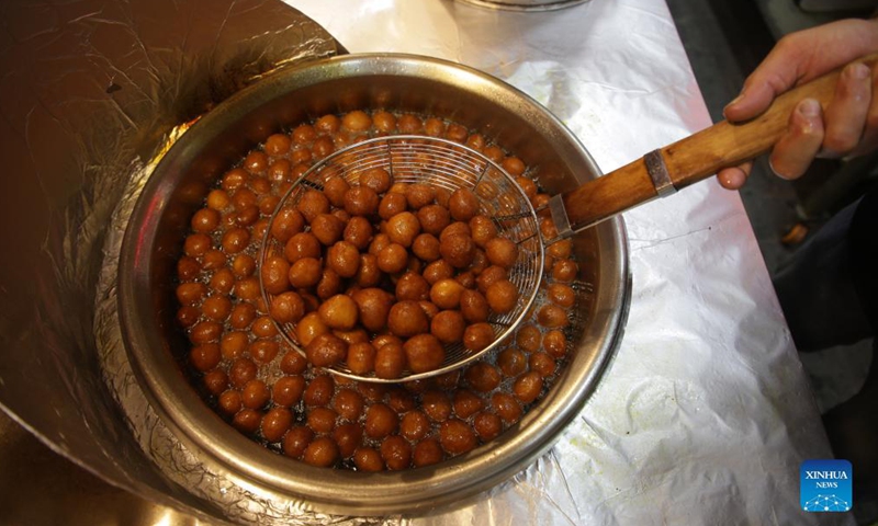 A Palestinian vendor makes Luqmat al Qadi, a traditional pastry made of leavened and deep fried dough, soaked in syrup, in Gaza City, on Nov. 21, 2021. (Photo by Rizek Abdeljawad/Xinhua)

