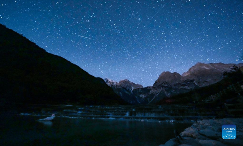 Photo taken on Dec. 14, 2021 shows a meteor of Geminids meteor shower at the Yulong Snow Mountain in Lijiang City, southwest China's Yunnan Province. The Geminids meteor shower of 2021 reached its peak on Tuesday.(Photo: Xinhua)