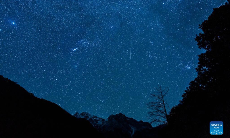 Photo taken on Dec. 14, 2021 shows a meteor of Geminids meteor shower at the Yulong Snow Mountain in Lijiang City, southwest China's Yunnan Province. The Geminids meteor shower of 2021 reached its peak on Tuesday.(Photo: Xinhua)