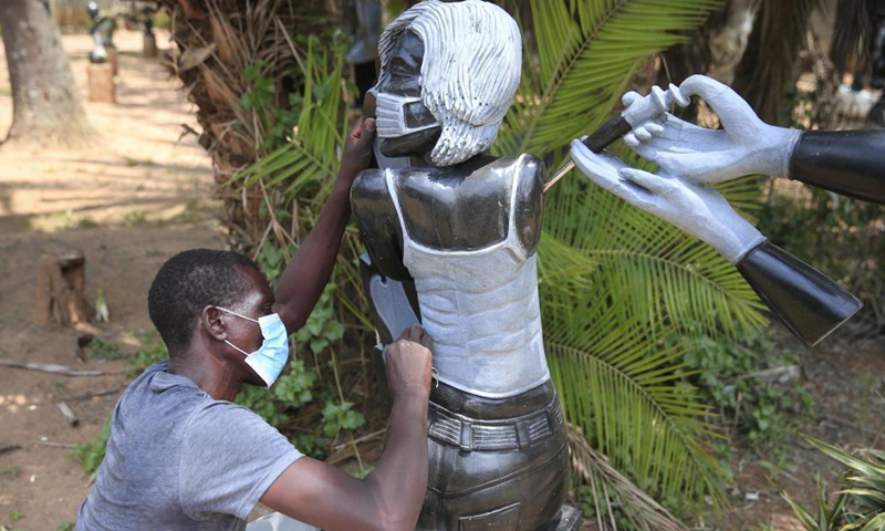 A worker polishes the sculpture titled Into the third wave made by David Ngwerume, one of Zimbabwe's most decorated artists, who is known for his pandemic-inspired art, in Harare, Zimbabwe, Dec. 8, 2021. Two of Zimbabwe's renowned stone sculptors will showcase their talent at the 9th Beijing International Art Biennale which will start next month. The Beijing International Art Biennale, which has taken place since 2002, promotes global harmony through contemporary artwork exhibitions.(Photo: Xinhua)