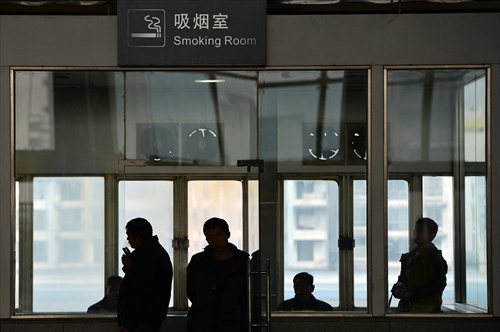 Smokers keep the door of a smoking room open at a railway station. Photo: CFP 