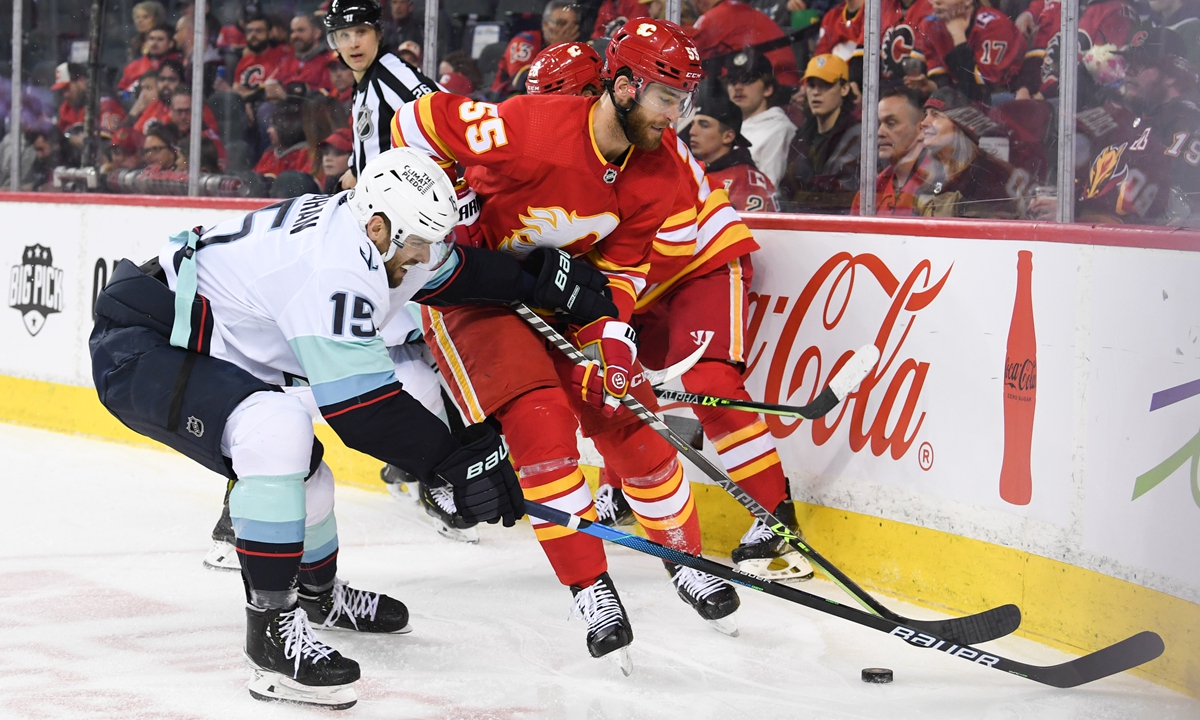 Seattle Kraken forward Riley Sheahan (left) and Calgary Flames defenseman Noah Hanifin battle for the puck on April 12, 2022 in Calgary, Canada. Photo: IC