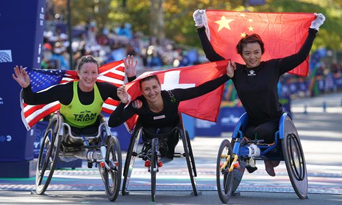 The 2018 TCS New York City Marathon Women's Wheelchair Division winner Manuela Schar of Switzerland (center) celebrates with second place Tatyana McFadden of the US (left) and third place Zou Lihong of China on Sunday. Photo: AFP