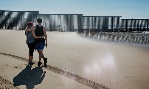 Onlookers from the US side view the US-Mexico border wall on Sunday. The Central American migrant caravan on Friday received warning that its chances of entering the US were almost nil. After traveling thousands of kilometers to Tijuana, migrants face the bleak reality of near-certain failure. Photo: AP 