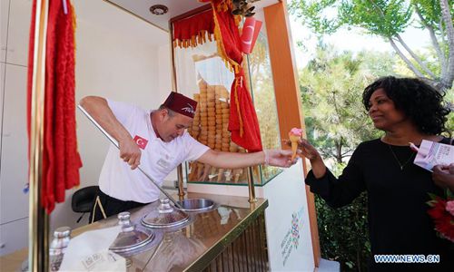 A visitor (R) tries Turkish ice cream at the Beijing International Horticultural Exhibition in Beijing, capital of China, July 3, 2019. The 