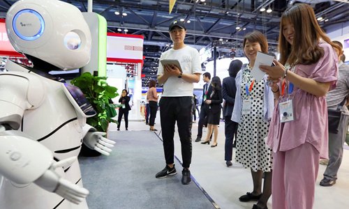 Visitors interact with a robot at a services trade fair in Beijing. Photo: IC