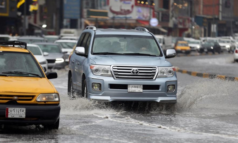 Vehicles run on flooded roads due to heavy rains in Baghdad, Iraq, on Nov. 21, 2020. (Xinhua)