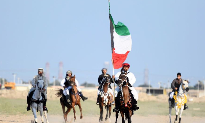 A man carrying a Kuwaiti national flag rides a horse during an equestrian show in Mubarak Al-Kabeer Governorate, Kuwait, Feb. 25, 2021. (Photo by Ghazy Qaffaf/Xinhua)