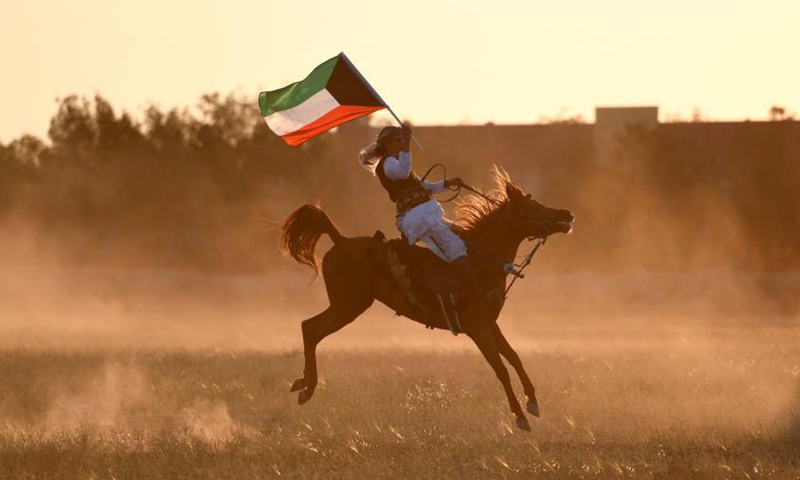 A man carrying a Kuwaiti national flag rides a horse during an equestrian show in Mubarak Al-Kabeer Governorate, Kuwait, Feb. 25, 2021. (Photo by Ghazy Qaffaf/Xinhua)