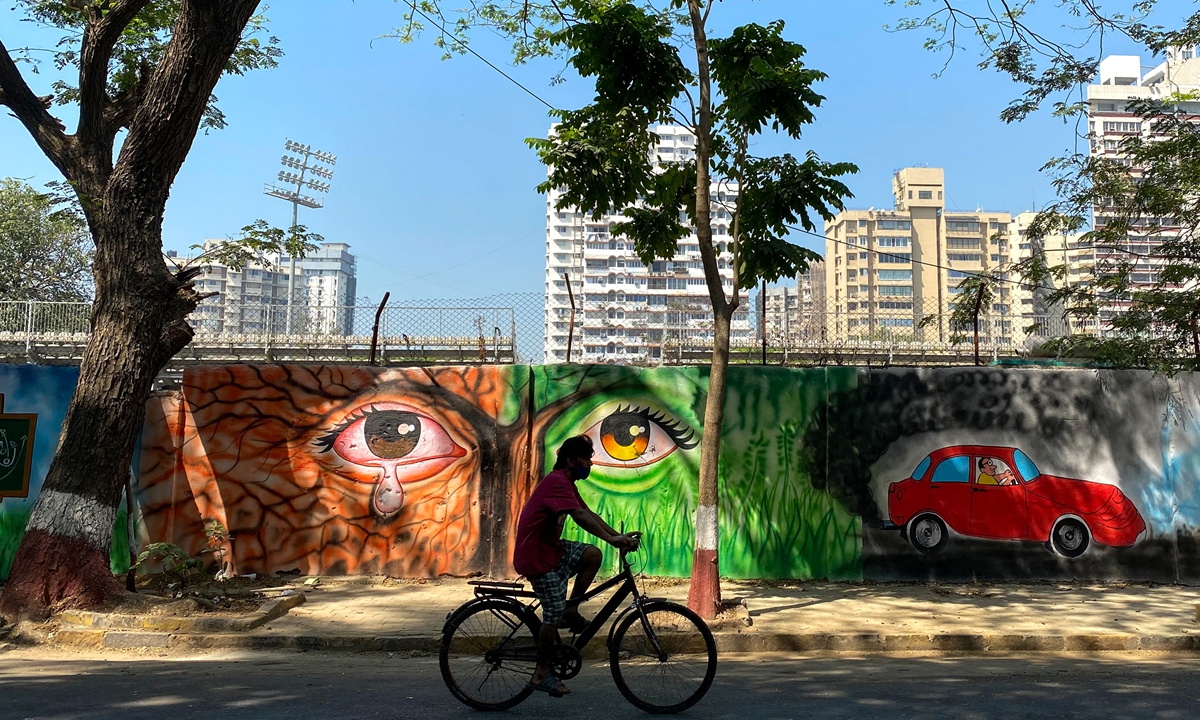 A cyclist rides past wall murals in Mumbai, India on Sunday. Photo: AFP