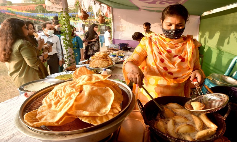 A vendor makes handmade cakes known as Pitha at a stall during a festival in Dhaka, Bangladesh on Feb. 27, 2021. (Photo: Xinhua)