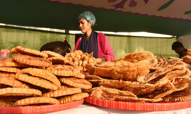 A vendor makes handmade cakes known as Pitha at a stall during a festival in Dhaka, Bangladesh on Feb. 27, 2021. (Photo: Xinhua)