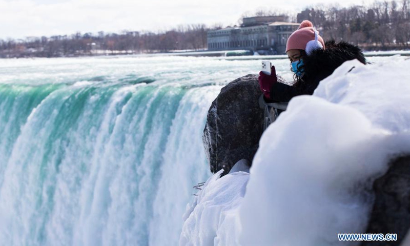 A visitor wearing a face mask takes photos in Niagara Falls, Ontario, Canada, on March 2, 2021.(Photo: Xinhua)