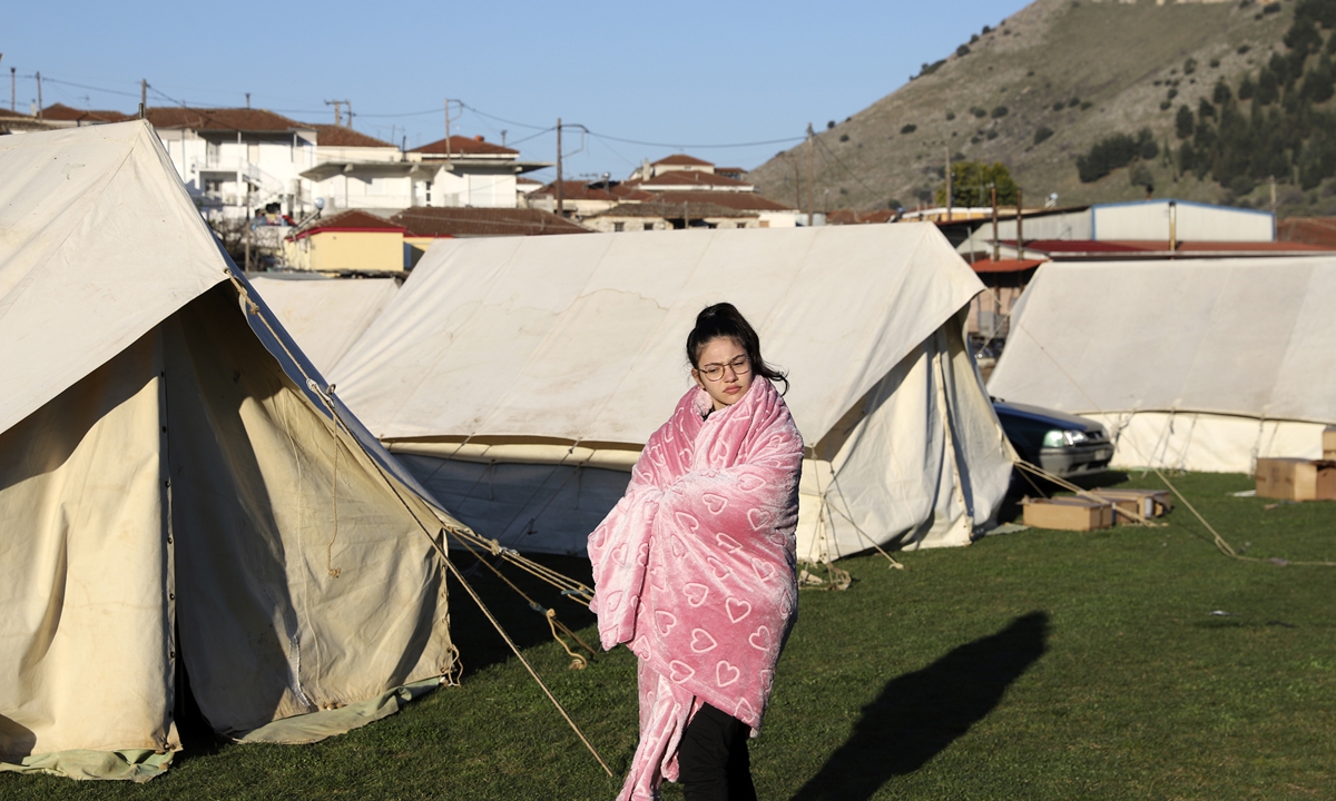 A girl standing outside a tent uses a blanket to stay warm after an earthquake in Damasi village, Greece, on Thursday. Fearful of returning to their homes, thousands of people spent the night outdoors after a powerful earthquake, felt across the region, damaged homes and public buildings. Photo: VCG