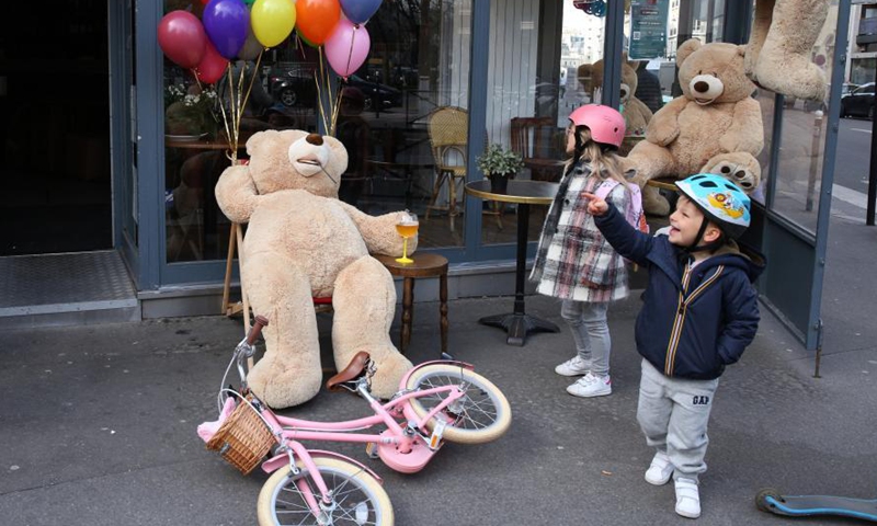 Children play with a giant teddy bear outside a restaurant in Paris, France, March 3, 2021. Giant teddy bears are seen at a restaurant which offers take away services in Paris. Restaurants, bars and cafes haved been all forced to shut down when the country entered into its second lockdown on Oct. 30, 2020. Photo:Xinhua