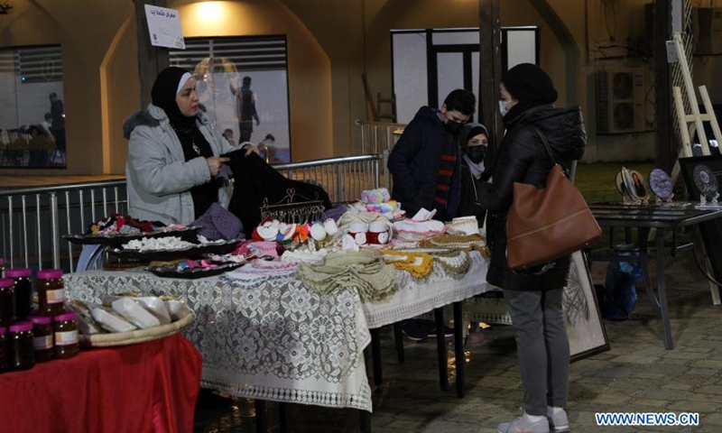 A Palestinian woman shows her handicrafts to a visitor at a handicraft exhibition in Gaza City, on March 6, 2021(Photo: Xinhua)