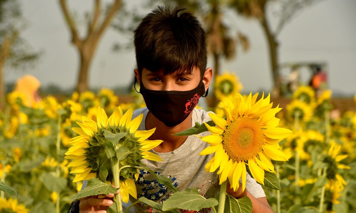 A boy poses for a photo at a sunflower field in Brahmanbaria district, Bangladesh, on March 6, 2021. (Xinhua)