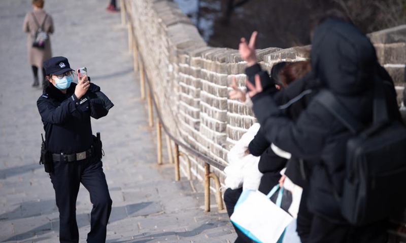 Wu Jingxuan, head of the female police force of Badaling Police Station, helps tourists to take photos on the Badaling Great Wall in Beijing, capital of China, March 7, 2021. (Photo: Xinhua)