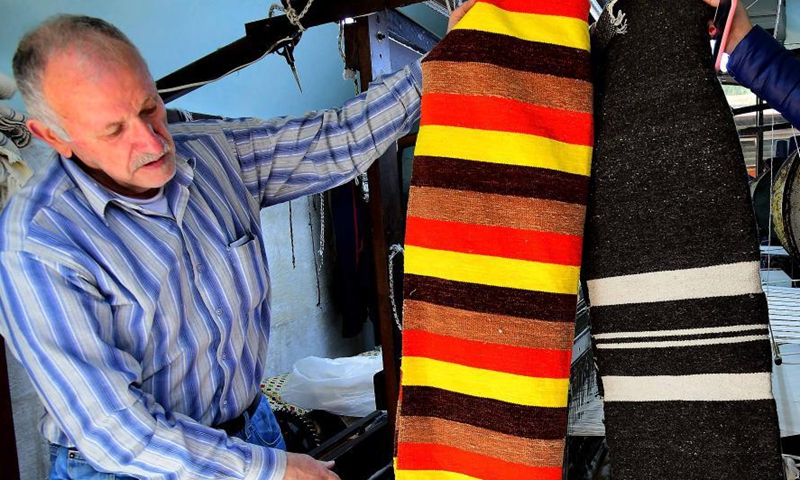 Munir Masdi shows textile products he weaved in traditional ways at an old loom in the capital Damascus on March 7, 2021. Masdi is one of the few remaining craftsmen who still work at old looms, a profession that might soon vanish in Syria.Photo:Xinhua