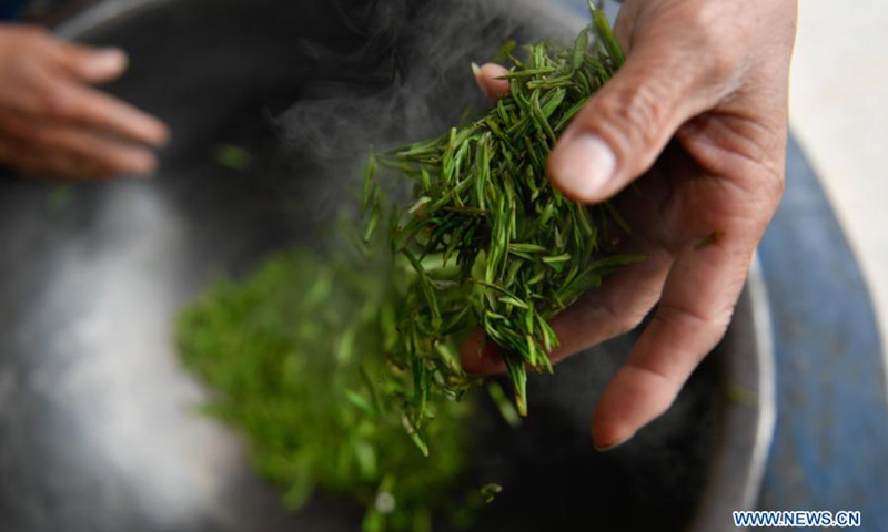 A tea farmer stirs and roasts fresh tea leaves with his bare hands at Zhuyuan Village, Hangzhou City of east China's Zhejiang Province, March 20, 2021.(Photo: Xinhua)