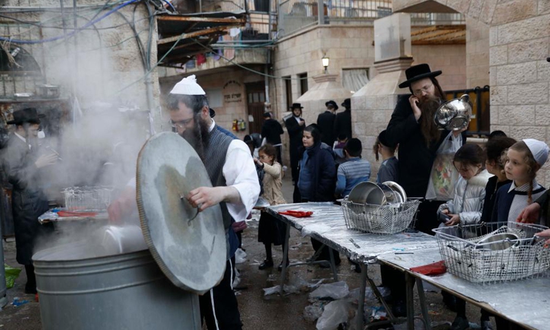 Ultra-Orthodox Jews dip their cookware in boiling water to remove remains of leaven during the final preparations before the start of the Jewish Passover holiday in Jerusalem on March 24, 2021.Photo:Xinhua